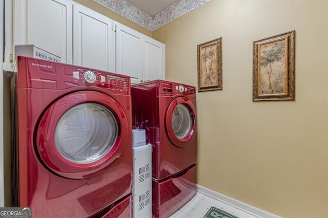 clothes washing area with washing machine and dryer, baseboards, and cabinet space