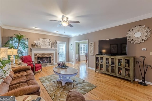 living area featuring ceiling fan, baseboards, wood finished floors, and a fireplace