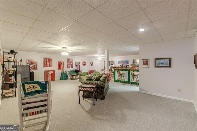carpeted living area with a drop ceiling and baseboards