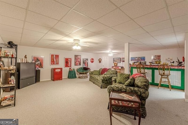 carpeted living area featuring a ceiling fan, baseboards, and a drop ceiling
