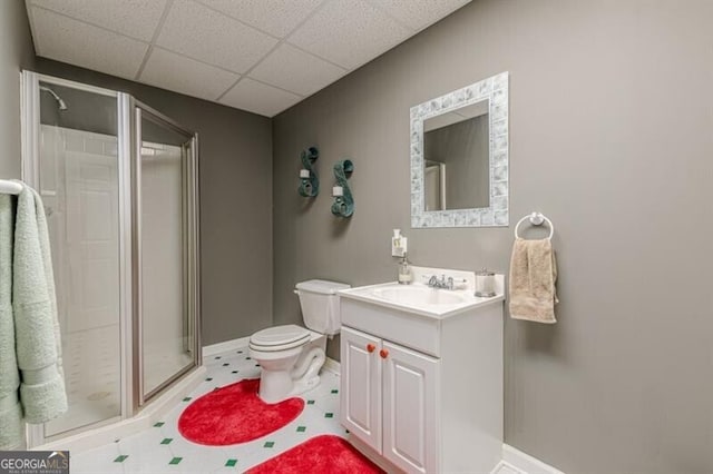 full bath featuring a shower stall, vanity, a drop ceiling, baseboards, and toilet