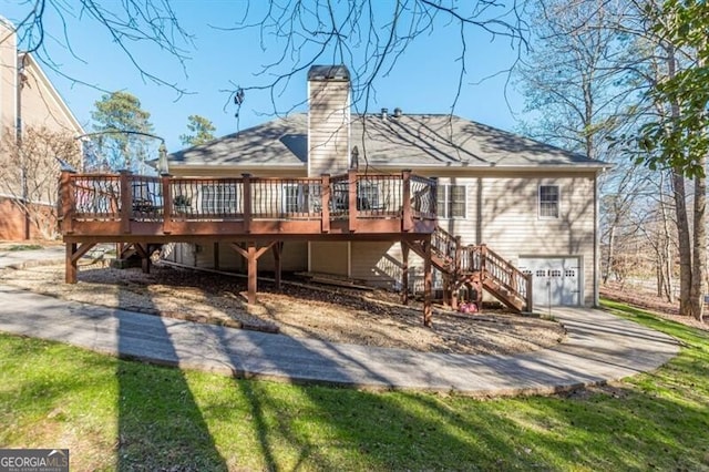 rear view of house featuring an attached garage, a wooden deck, a chimney, and stairs