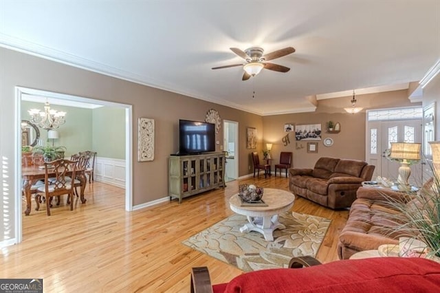 living room with ceiling fan with notable chandelier, light wood-style flooring, and crown molding