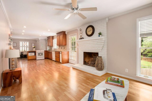 living room with ceiling fan, light hardwood / wood-style floors, ornamental molding, and a fireplace