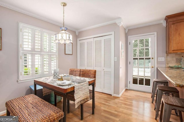 dining space featuring crown molding, a wealth of natural light, and light hardwood / wood-style flooring