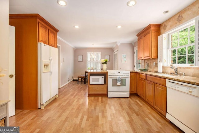 kitchen featuring kitchen peninsula, white appliances, sink, pendant lighting, and light hardwood / wood-style floors