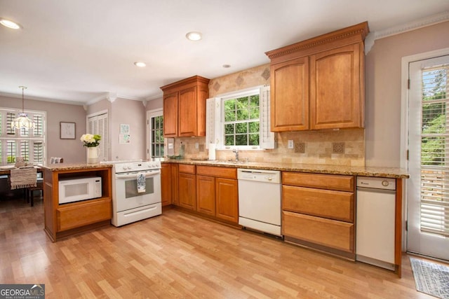 kitchen featuring tasteful backsplash, light hardwood / wood-style flooring, kitchen peninsula, pendant lighting, and white appliances