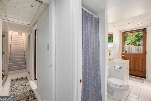 bathroom with a drop ceiling, vanity, tile patterned flooring, toilet, and curtained shower