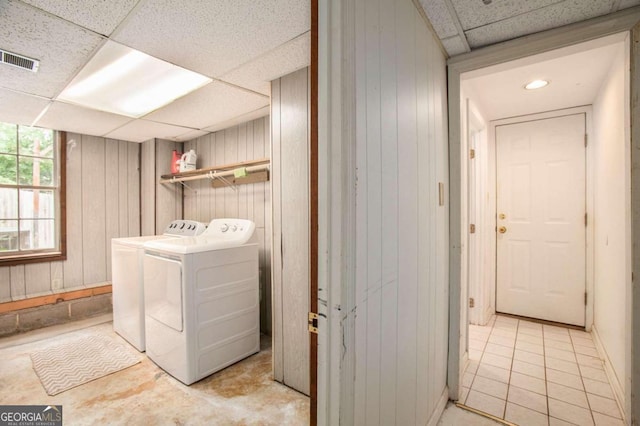 clothes washing area with wooden walls and washer and dryer