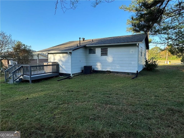 rear view of house with a deck, a yard, and central AC