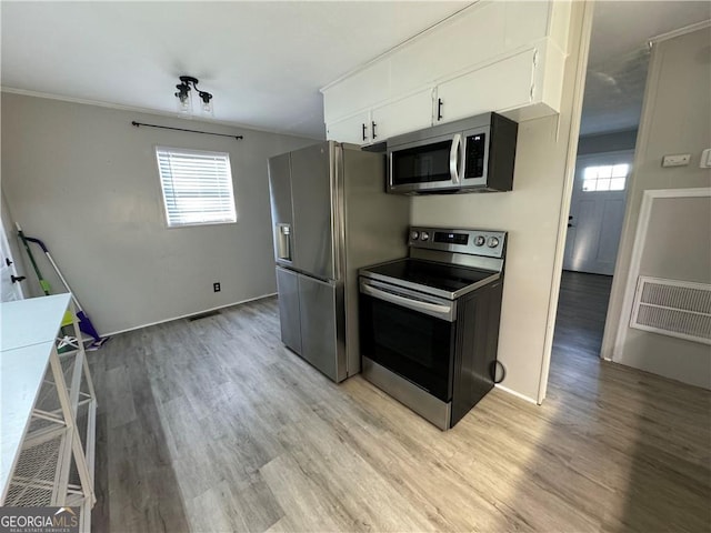 kitchen featuring white cabinets, appliances with stainless steel finishes, light hardwood / wood-style floors, and a healthy amount of sunlight