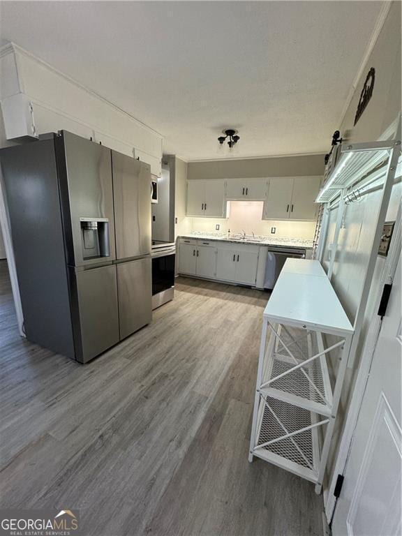 kitchen featuring white cabinets, appliances with stainless steel finishes, hardwood / wood-style flooring, and sink