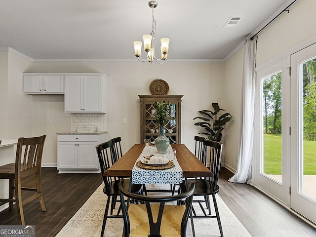 dining area featuring crown molding, dark hardwood / wood-style flooring, and an inviting chandelier