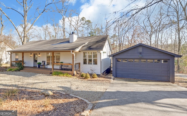 ranch-style home featuring a chimney, concrete driveway, an outbuilding, covered porch, and a garage