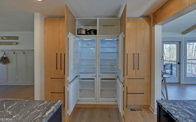 kitchen featuring dark stone countertops, light hardwood / wood-style flooring, and light brown cabinetry