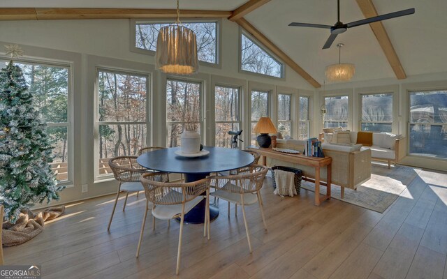 sunroom / solarium featuring ceiling fan with notable chandelier and lofted ceiling with beams