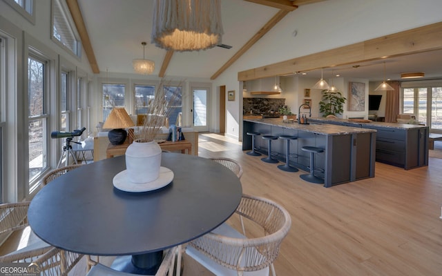 dining area with high vaulted ceiling, sink, light hardwood / wood-style flooring, beamed ceiling, and a notable chandelier