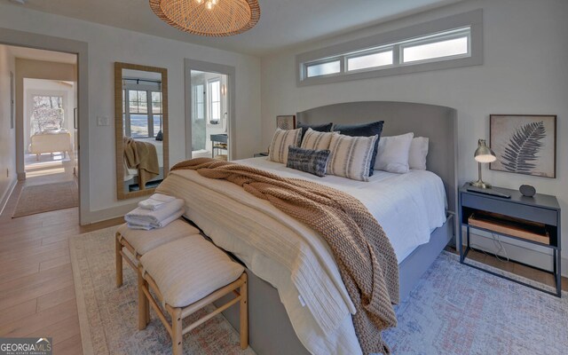 bedroom with light wood-type flooring and ensuite bath