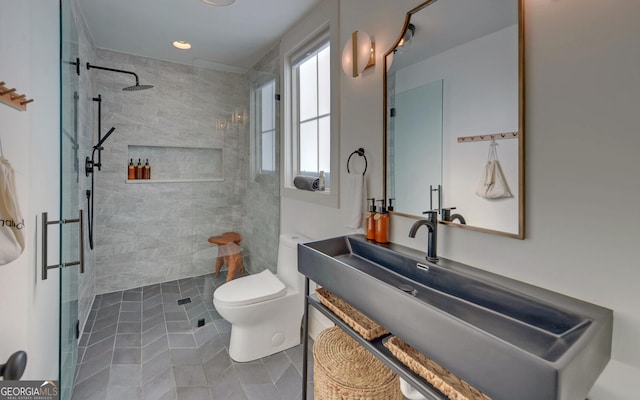 bathroom with tile patterned flooring, a tile shower, toilet, and vanity