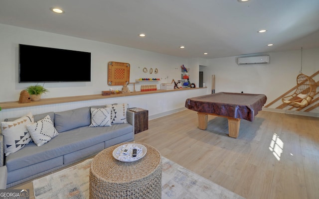 rec room with light hardwood / wood-style floors, a wall unit AC, and billiards