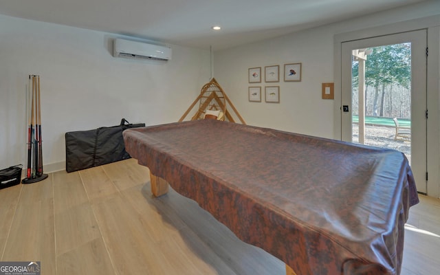 recreation room with light hardwood / wood-style floors, an AC wall unit, and billiards