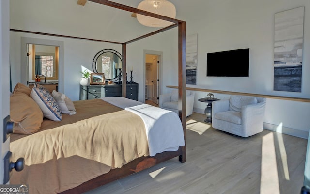 bedroom featuring ensuite bathroom, hardwood / wood-style floors, and high vaulted ceiling