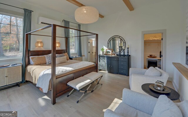 bedroom featuring beamed ceiling, a wall mounted air conditioner, and light hardwood / wood-style flooring