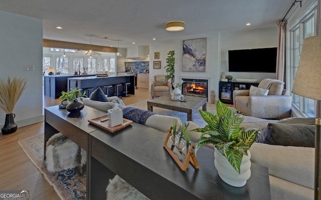 living room with light wood finished floors, a glass covered fireplace, and recessed lighting