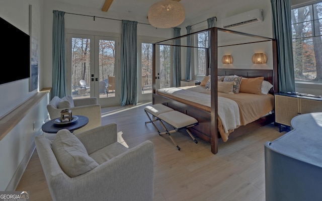 bedroom featuring french doors, wood finished floors, an AC wall unit, and access to outside