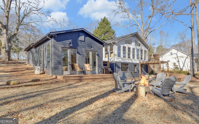 rear view of property with a fire pit, a sunroom, and a deck