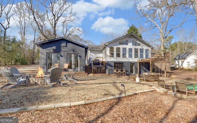 rear view of property with a patio area, a deck, french doors, a fire pit, and a sunroom