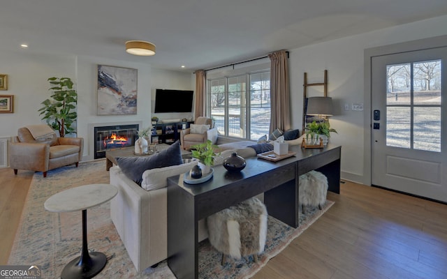 living room with light wood-type flooring, a glass covered fireplace, and recessed lighting