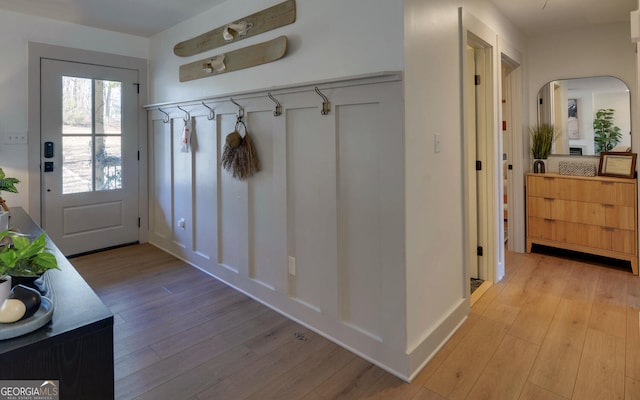 mudroom featuring arched walkways and light wood finished floors
