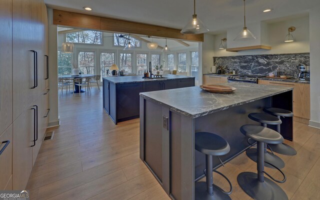 kitchen with beamed ceiling, backsplash, pendant lighting, a breakfast bar, and a kitchen island