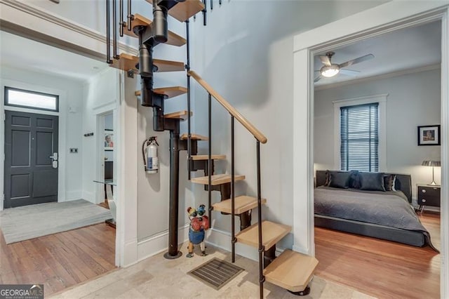 staircase featuring hardwood / wood-style floors, ceiling fan, and ornamental molding