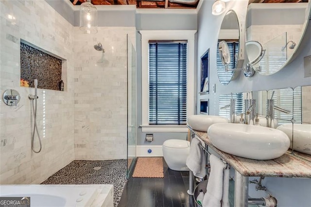 bathroom featuring a tile shower, vanity, wood-type flooring, and toilet