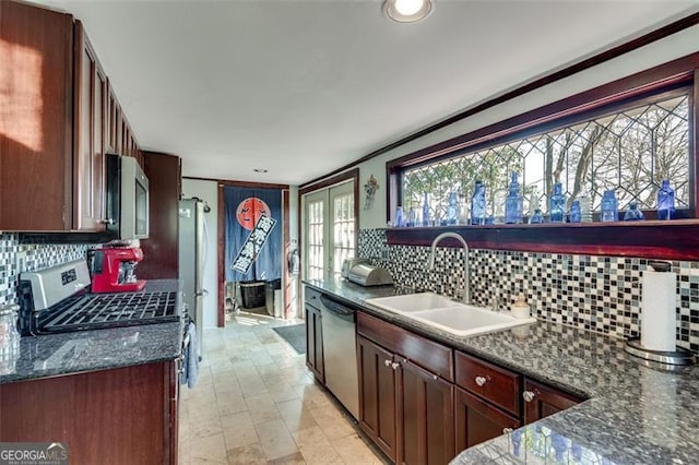 kitchen with french doors, tasteful backsplash, dark stone counters, stainless steel appliances, and sink