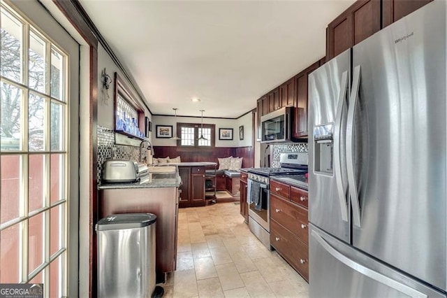 kitchen featuring pendant lighting, sink, decorative backsplash, appliances with stainless steel finishes, and kitchen peninsula