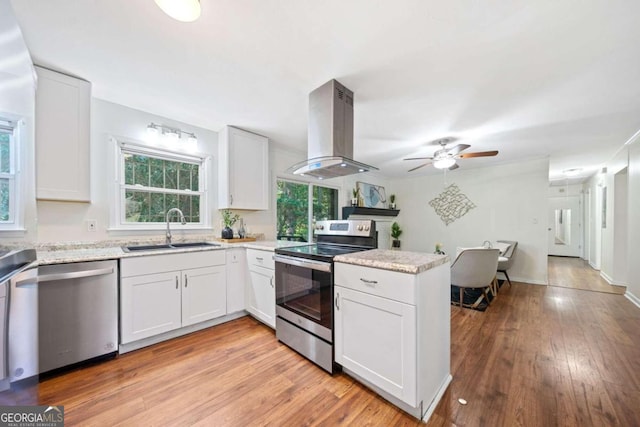 kitchen with sink, appliances with stainless steel finishes, light hardwood / wood-style floors, white cabinetry, and extractor fan