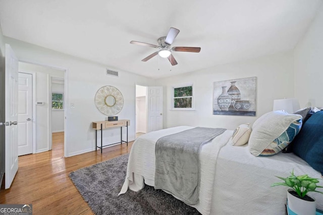 bedroom with hardwood / wood-style flooring, ceiling fan, and multiple windows