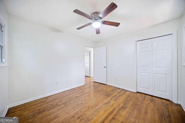 unfurnished bedroom featuring ceiling fan, a closet, and wood-type flooring