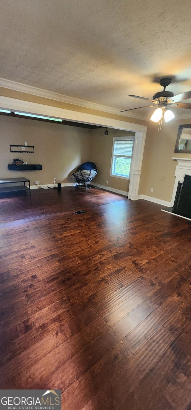 interior space featuring ceiling fan, dark hardwood / wood-style flooring, ornamental molding, and a textured ceiling