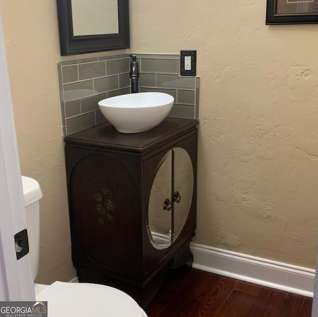 bathroom with decorative backsplash, toilet, wood-type flooring, and vanity