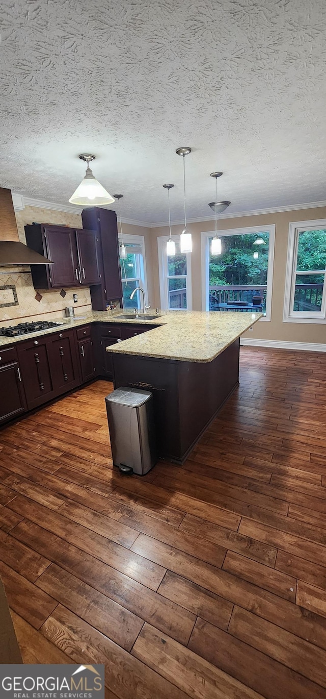 kitchen featuring a kitchen breakfast bar, decorative light fixtures, a kitchen island, extractor fan, and gas cooktop