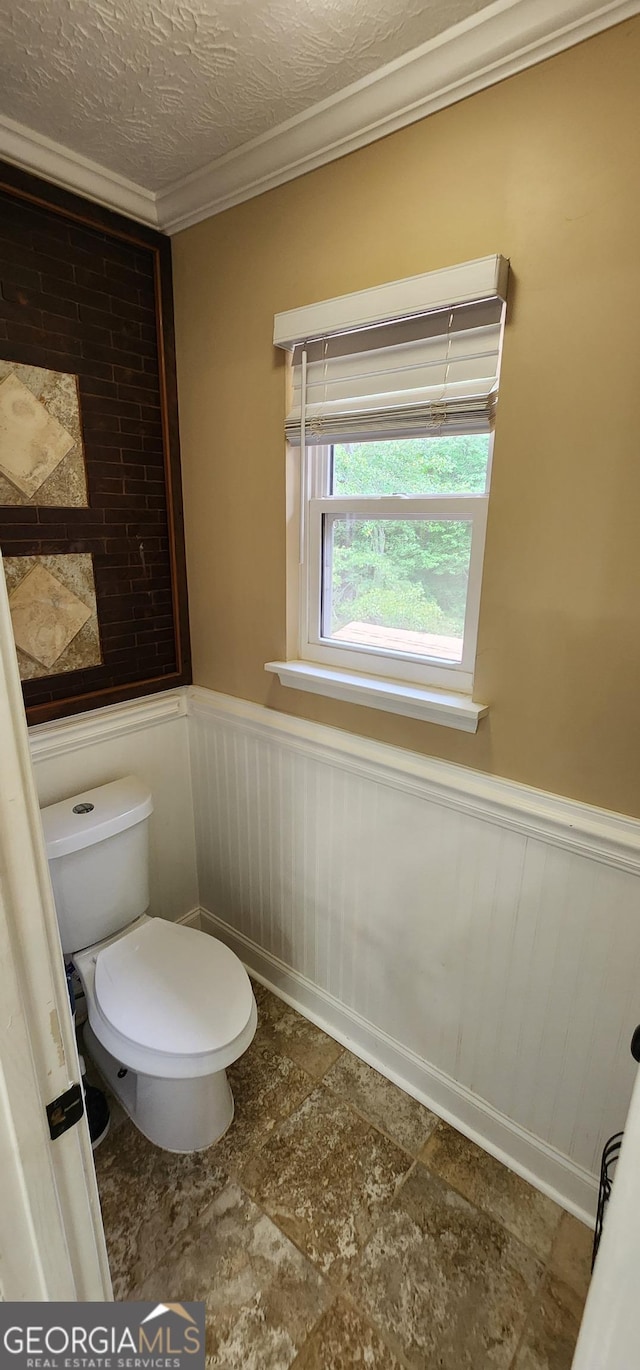 bathroom featuring toilet, a textured ceiling, and ornamental molding