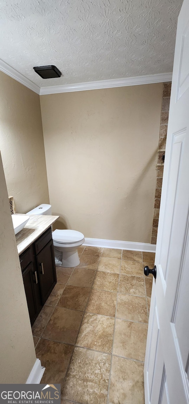 bathroom with toilet, vanity, a textured ceiling, and ornamental molding