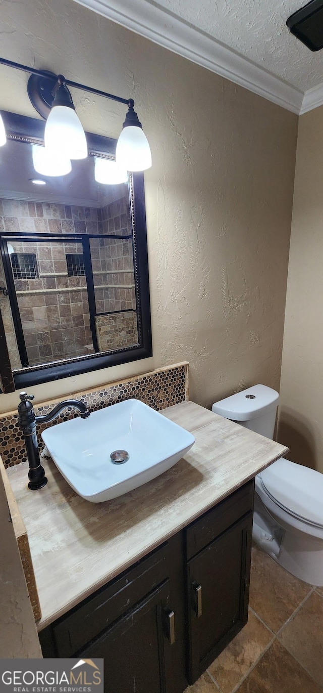 bathroom with vanity, toilet, ornamental molding, and a textured ceiling