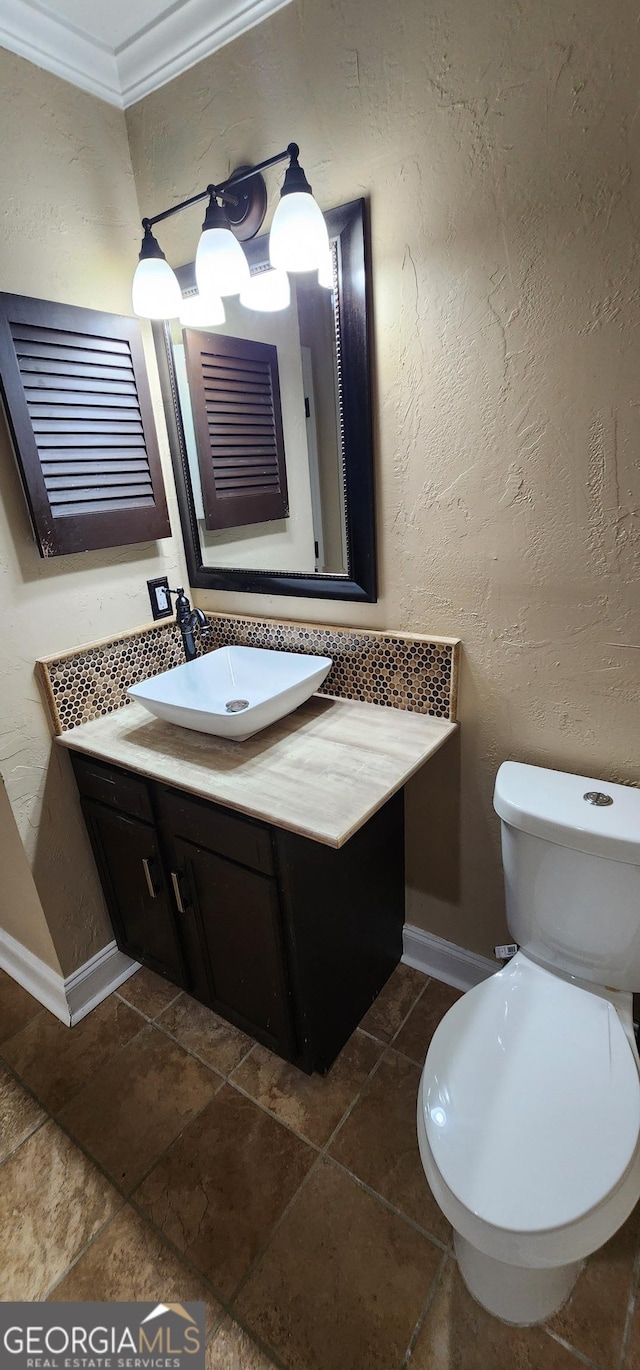 bathroom featuring decorative backsplash, toilet, crown molding, and vanity