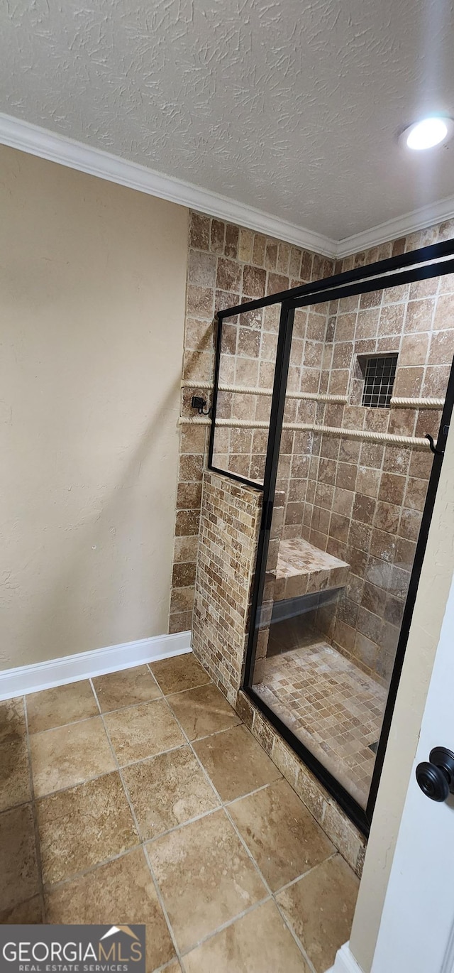 bathroom featuring a tile shower, crown molding, and a textured ceiling