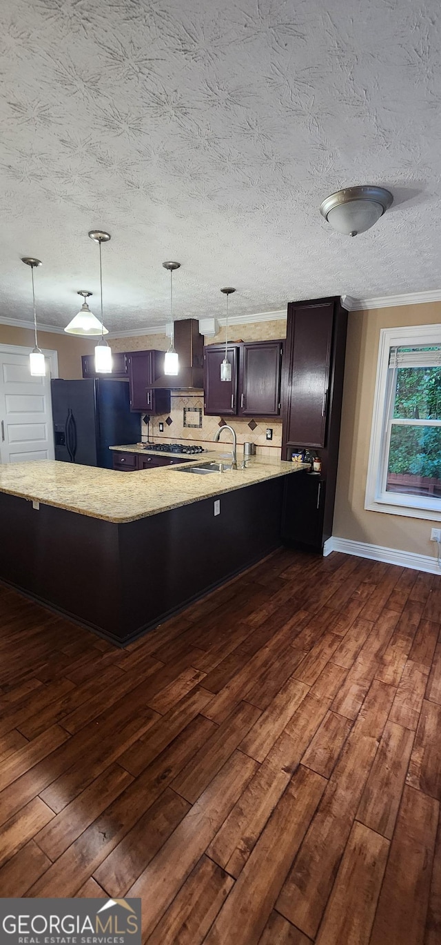 kitchen featuring backsplash, hanging light fixtures, dark hardwood / wood-style floors, black fridge with ice dispenser, and kitchen peninsula